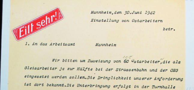 Ausschnitt eines Faksimiles eines kursiv getippten Briefs vom 30.6.1942: „Wir bitten um Zuweisung von (60) 100 Ostarbeiter(n), die als Gleisarbeiter […] bei […] der OEG eingesetzt werden sollen.“