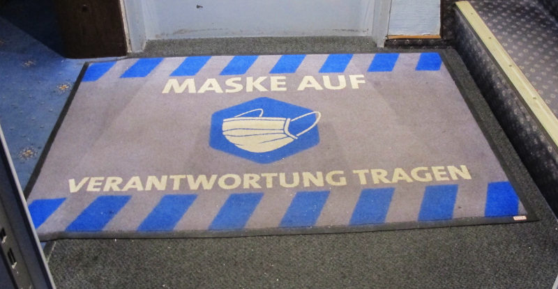 Fußmatte mit Aufschrift „Maske auf/Verantwortung tragen“