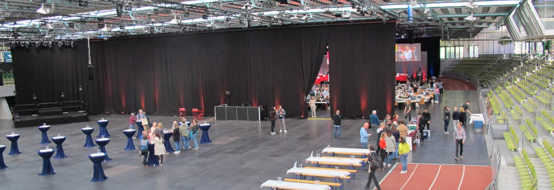 Foto einer großen und weitgehend leeren Halle mit ein paar Menschen auf einem Haufen.