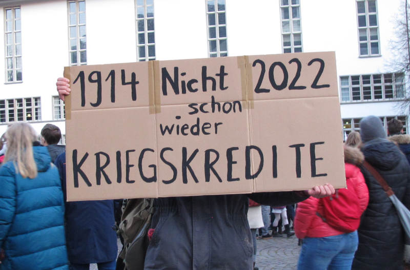 DemoteilnehmerIn mit Schild: „1914 – 2022 – Nicht schon wieder Kriegskredite”