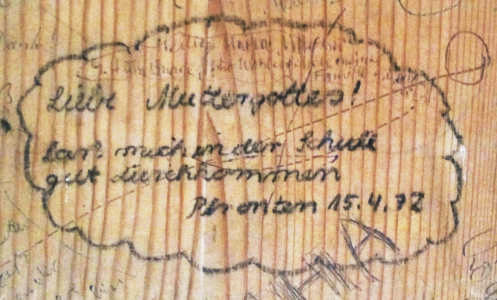 In stilisierte Wolke auf Holz in Kinderschrift geschrieben: Liebe Muttergottes! laß mich in der Schule gut durchkommen.  Pfronten 15.4.72