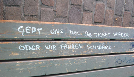 Handwritten letters in white on wooden planks: “Gebt uns das 9-Euro-Ticket wieder oder wir fahren schwarz“