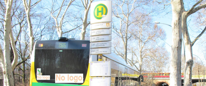 Foto: Bushaltestelle mit abfahrendem Bus, im Hintergrund eine querende S-Bahn