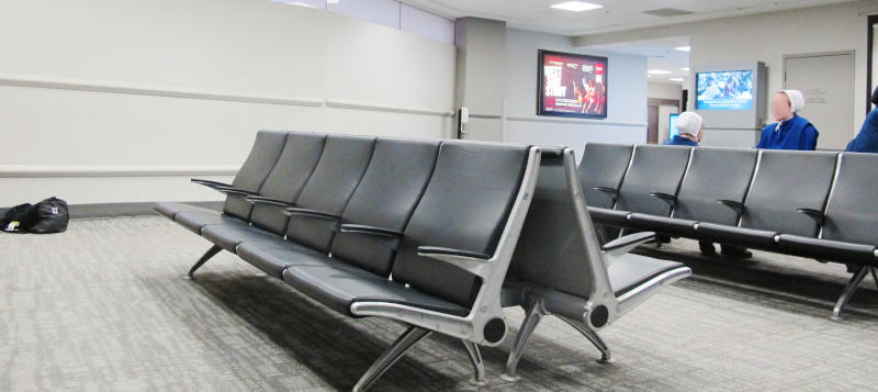 A room with a carpet and some rows of chairs looking exactly as if they were recycled from airports.