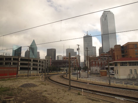 Skyscrapers in front or an overcast sky (for fairness: on the photo, there *is* a bit of blue sky) and a dark railway in the foreground.