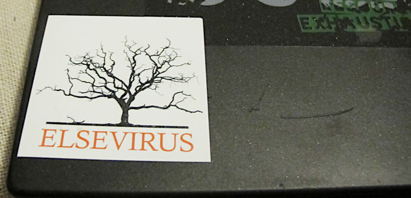 Foto eines Notebookdeckels mit Aufkleber „Elsevirus“ und einem vertrockneten Baum (ein Spoof des Elsevier-Logos)