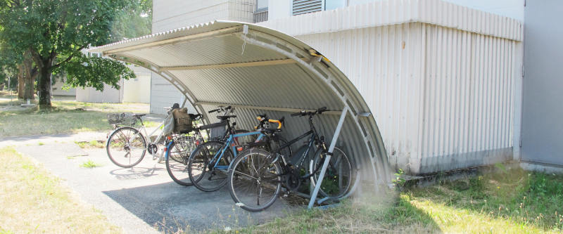 Ein Fahrradständer mit einem Regenschutz aus gebogenem Wellblech