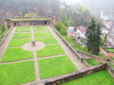 Durch Gras angedeutete Anlage eines französischen Renaissancegartens in einer dem Berg durch Mauern abgezwungenen Ebene.