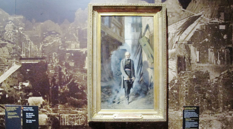 Ein Bild, auf dem ein Mann durch eine zerstörte Stadt geht, vor einem großen Foto-Hintergrund mit einer zerstörten Stadt.