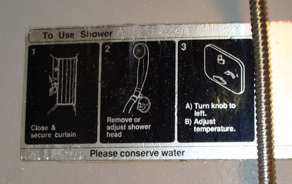 A sign "To use shower" in three steps: close and secure curtain, remove or adjust shower head, turn knob to left, adjust temperature. Please conserve water.