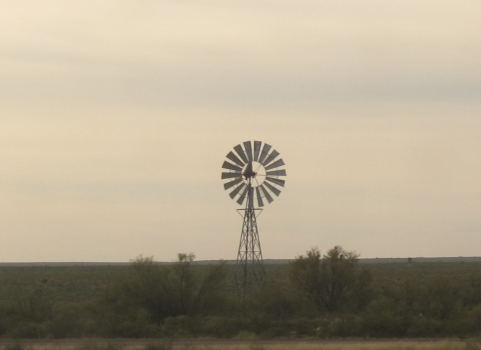 A western wind wheel against a pinkish sky