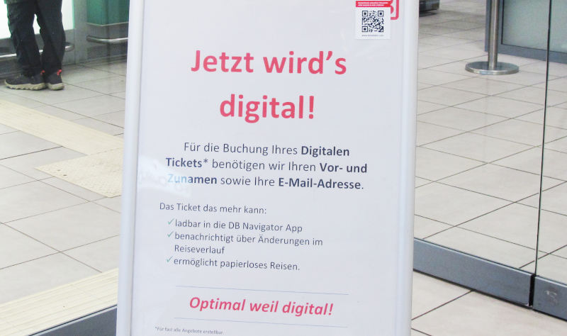 Ein Plakataufsteller auf einem gefliesten Boden: „Jetzt wird's digital! Für die Buchung Ihres Digitalen Tickets benötigen wir Ihren Vor- und Zunamen sowie Ihre E-Mail-Adresse“.