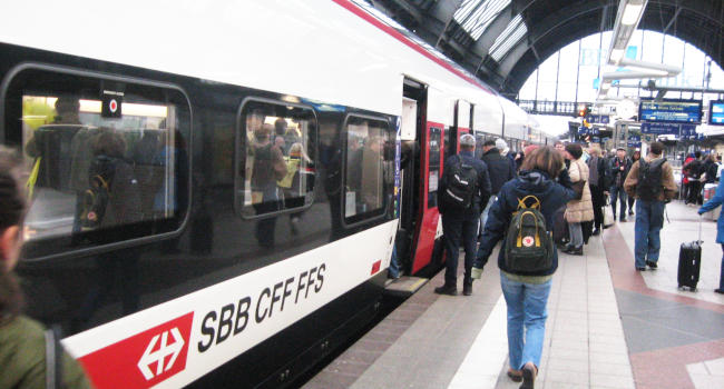 People entering a white high-speed rail car.  There is a prominent SBB CFF FFS painted on it.  On the right part of the image, there is platform 2 of Karlsruhe main station.