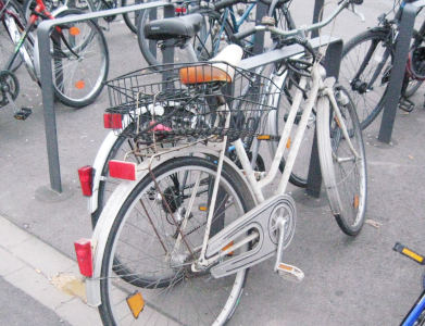 A fairly run-down white bicycle within an open-air bicycle parking facility.