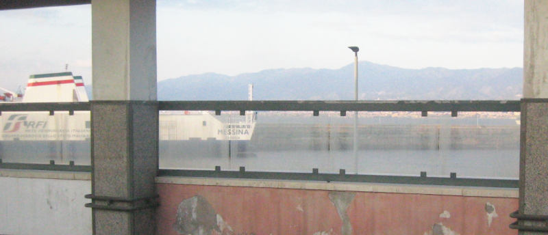 Again, seen through railway station construction: a large ship with green-white-blue decor, the FS logo, and the name Messina. station.