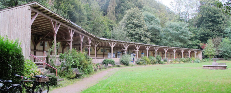 Eine leicht gerundete, vielleicht fünf Meter tiefe und hundert Meter breite, aus Holz errichtete Halle.