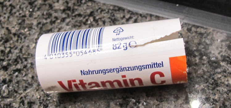 Der Unterteil von einem Vitaminbrauseröhrchen (Aufschrift „Nahrungsergänzungsmittel Vitamin C“), wie beschrieben abgeschnitten und mit einer keilförmigen Nut versehen.