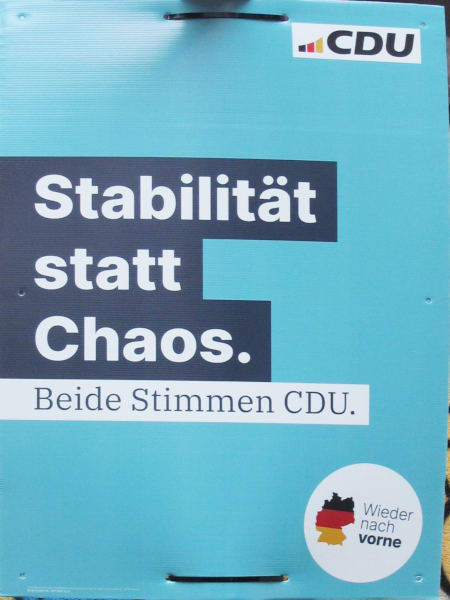 Weiß auf schwarz auf blauem Grund: "Stabilität statt Chaos", unten ein Kreis mit Nationalfarben und "Wieder nach vorne".