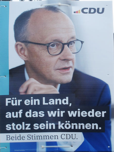 Ein Kopf mit nicht all zu viel Haaren und Brille, darunter eine Anzugjacke, weiße Schrift auf schwarzem Grund: "Für ein Land auf das wir wieder stolz sein können".