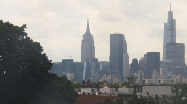 Some sky scrapers in front of a sky; in the middle of the picture, there is the characteristic shape of the Empire State Building.