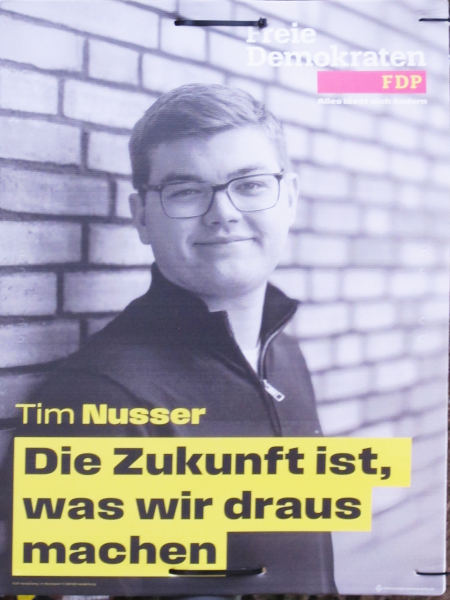 Ein Seitenportrait eines fülligen Menschen mit Brille und Seitenscheitel vor einer Klinkerwand, davor schwarz auf gelb: "Die Zukunft ist, was wir daraus machen".