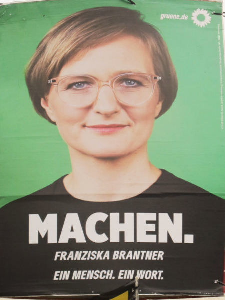 Ein mittelaltes Gesicht mit kurzen Haaren und Brille vor grünem Hintergrund.