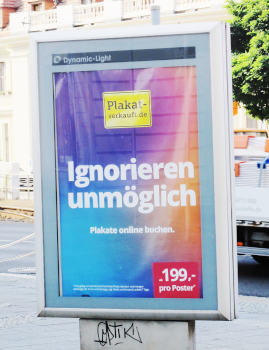 Ein verglaster Plakatständer eines Unternehmens namens „Dynamic Light“ mit dem großen Claim „Ignorieren unmöglich“ auf einem blau-türkis-magenta-orange Verlauf und der Aufforderung, Plakate online zu buchen.