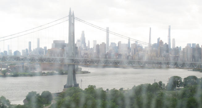 A bridge over a wide river, and lots of skyscrapers behind it.