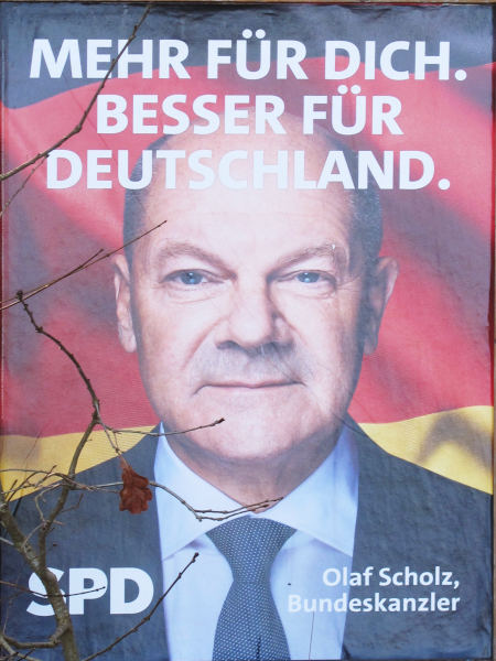 Ein Kopf mit wenig Haaren von einem schwarz-rot-gelben Hintergrund, darüber in weiß: "Mehr für dich. Besser für Deutschland"