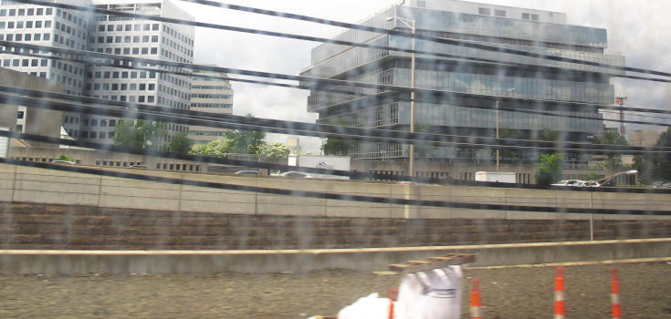 A modern building with a glass facade and a few storeys, growing towards the top.  In the foreground, suspended cables and trash.