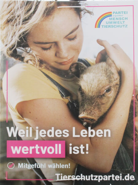 Ein Mensch hält ein Ferkel in der Hand und blickt es liebevoll an.  Darüber: "Weil jedes Leben wertvoll ist.  Mitgefühl wählen"