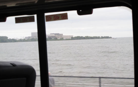 A stretch of water photographed through a dirty train window; it's grey water with waves.