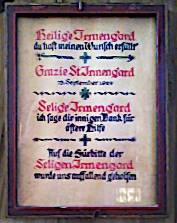 Eine gerahmte Tafel in Frakturschrift, auf der u.a. steht: „Heilige Irmengard, du hast meinen Wunsch erfüllt […] Auf die Fürbitte der Seligen Irmengard wurde uns auffallend geholfen“.